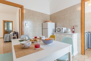 Una cucina moderna con un tavolo da pranzo apparecchiato per la colazione, inclusa una ciotola di frutta, una tazza di tè e un piatto di pasticcini.