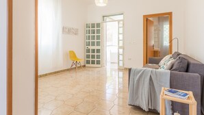 Un salon spacieux avec un canapé gris, un fauteuil jaune et une table d’appoint en bois.