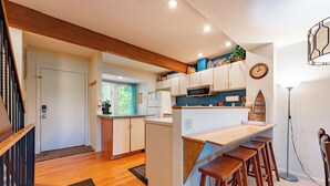 Een moderne keuken met houten barstoelen, een magnetron en een koelkast.