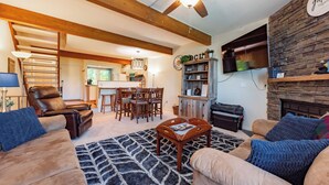 Een woonkamer met een open haard, een plafondventilator en een stenen muur.