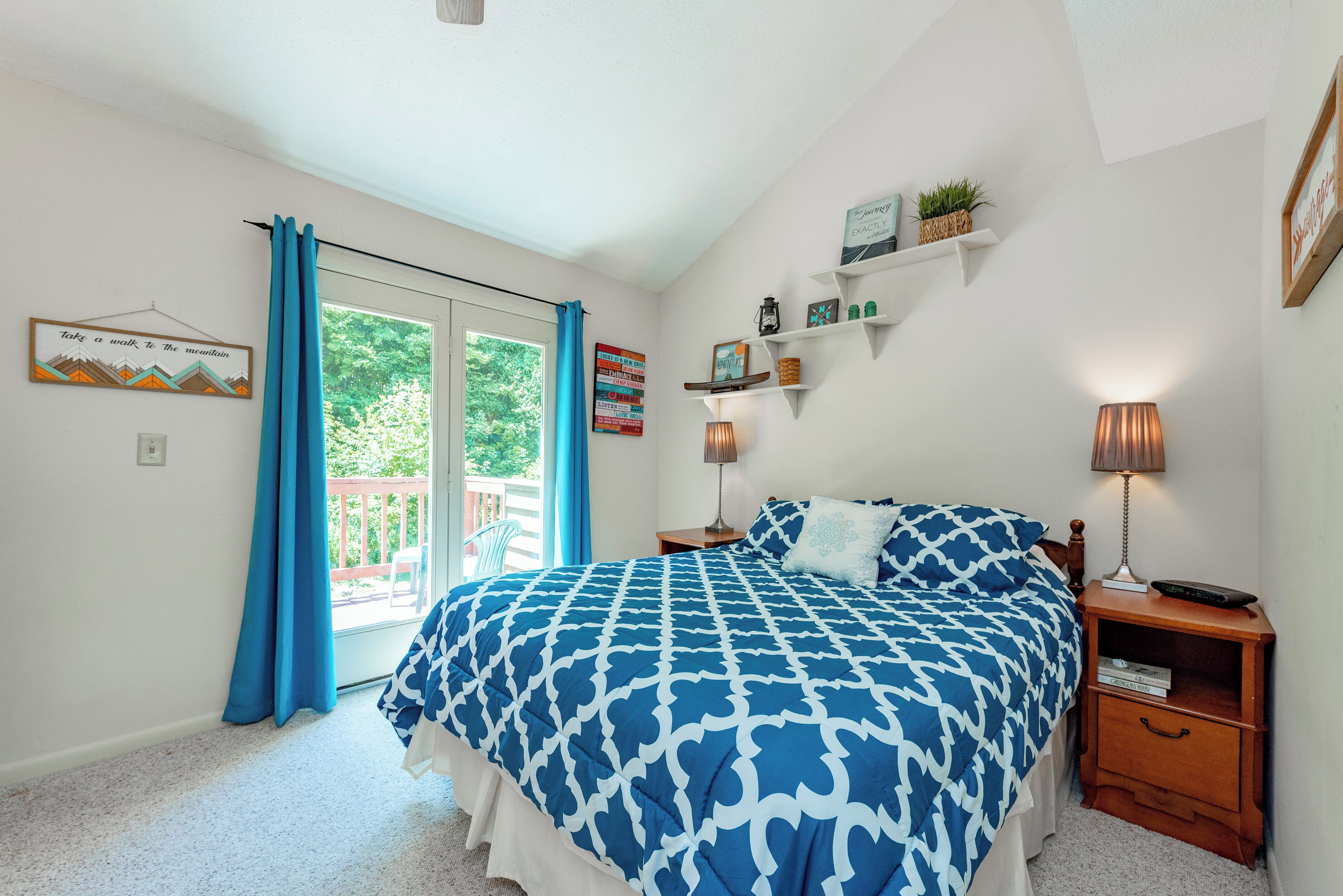 A bedroom with a large bed, a nightstand, a lamp, and a window with curtains.