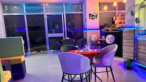 A modern dining area with a glass partition, a red table, and several chairs. - Addis Amba Guest House (Addis Ababa)
