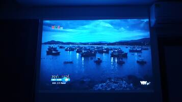 A projection of a coastal scene with boats on water, a cloudy sky, and a mountainous background.