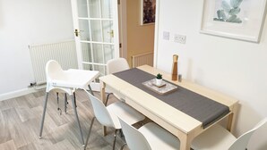A dining area with a table, chairs, a radiator, a door with glass panels, and a framed plant on the wall. - Gorgeous Thornton-le-Dale 2 Bedroom Cottage & Garden, Cosy Family Friendly, WIFI (Thornton-le-Dale)