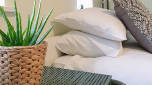 A neatly arranged room with a bed, pillows, a hanging laundry rack, a woven basket with a plant, and a small table. - Gorgeous Thornton-le-Dale 2 Bedroom Cottage & Garden, Cosy Family Friendly, WIFI (Thornton-le-Dale)