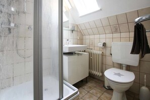 Une salle de bain avec douche, toilettes et lavabo.