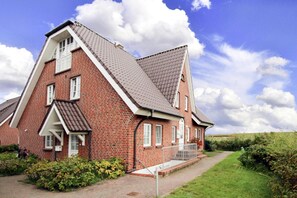 A red brick house with a steeply pitched roof, white trim, and a small front porch. - Ferienwohnung, St. Peter-Ording (St. Peter-Ording)