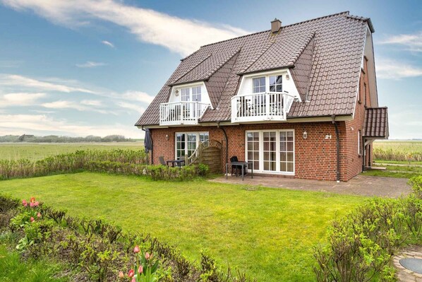 A two-story house with a brick exterior, a large front porch, and a well-maintained lawn. - Ferienwohnung, St. Peter-Ording (St. Peter-Ording)