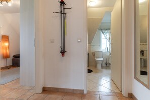 A hallway leading to a bathroom with a toilet, sink, and shower. - Ferienwohnung, St. Peter-Ording (St. Peter-Ording)