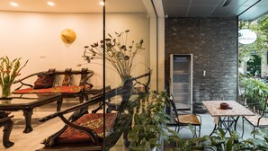 A modern interior with a glass partition, wooden furniture, and a variety of plants. - Narcissus Hotel and Apartment (Hanoi)