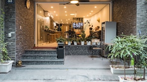 A hotel entrance with a modern design, featuring a brick wall, a ceiling fan, and a TV screen in the background. - Narcissus Hotel and Apartment (Hanoi)