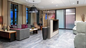A modern living room with a grey sofa, a beige armchair, a coffee table, and a fireplace.