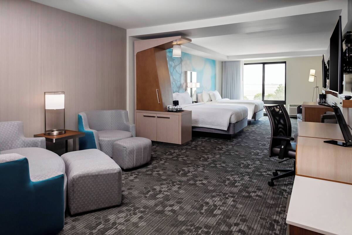 A hotel room with a bed, two seating areas, a desk, and a TV.