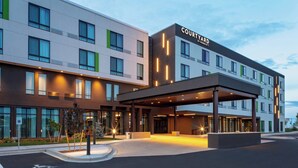 A Courtyard by Marriott hotel with a modern design, featuring a covered entrance and a parking lot.