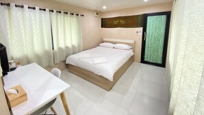 Una habitación de hotel con cama, escritorio y ventana con cortinas.