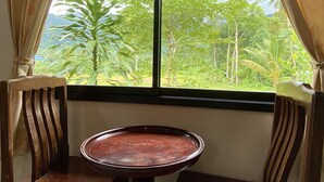 Una habitación con un ventanal grande, una silla de madera y una pequeña mesa.