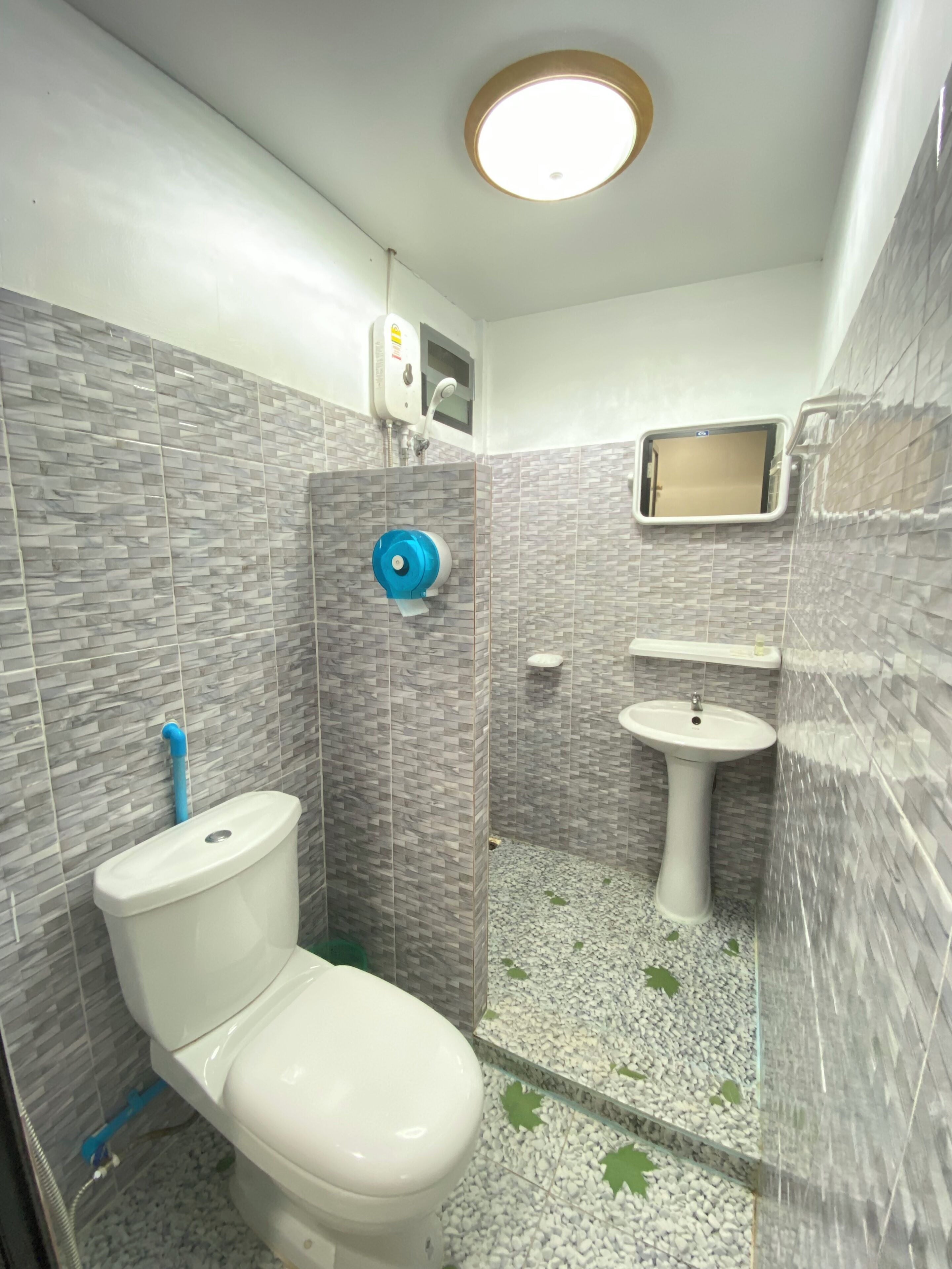 A bathroom with a toilet, bidet, and sink, tiled with a gray pattern.