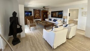 A spacious living room with a sofa set, a statue, and artwork on the walls.