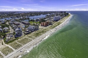 Una zona residencial costera con propiedades frente al mar, un puerto deportivo y un puente a lo lejos.