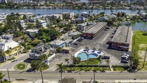 A residential area with a large parking lot, a swimming pool, and a view of a body of water. - Sunset Cove: One-Bedroom in Treasure Island (Treasure Island)