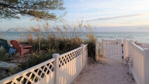 A beach pathway with a white fence, leading to the beach.