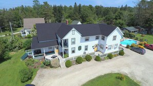 A two-story building with a swimming pool, a covered patio, and a gravel driveway. - Anchorage House & Cottages - Anchorage House (Hubbards)