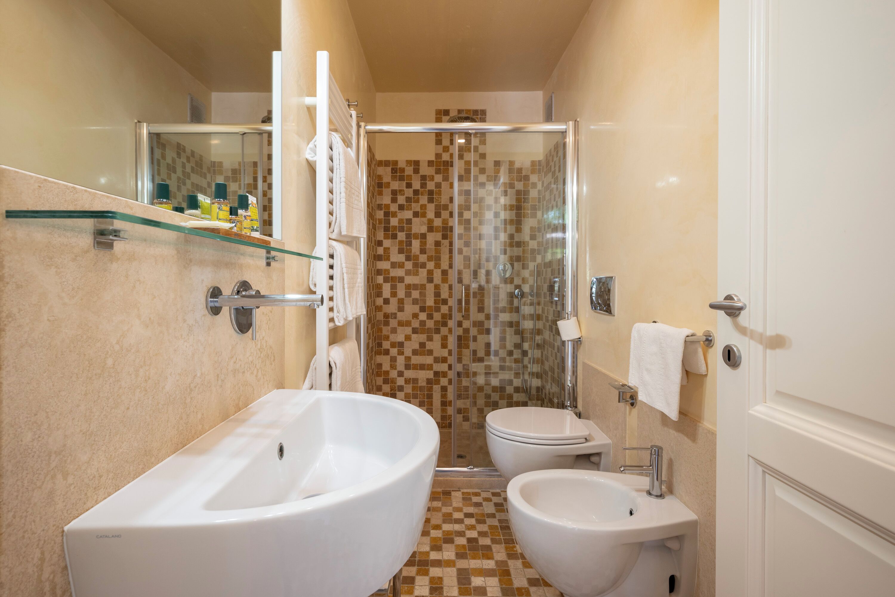Un bagno con vasca, due lavandini, un water e zona doccia.