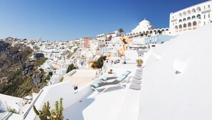 Un pueblo costero con edificios blancos, una estructura cúpula destacada y una colina pronunciada.