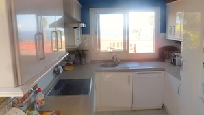 Una cocina con gabinetes blancos, un fregadero, un microondas y un reloj en la pared.