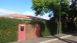 Un edificio con puerta roja, rodeado de abundante follaje verde y un tejado de tejas.