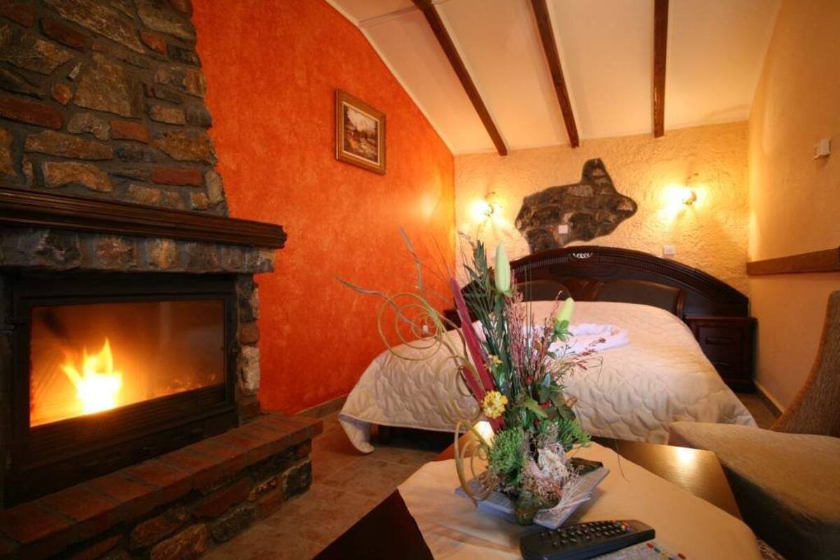 A cozy room with a fireplace, a bed, and a decorative plant arrangement.