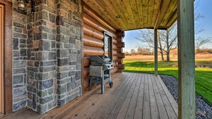 A wooden deck with a grill and a stone wall. - North Shore Cabin w/ Fire Pit By Gooseberry Falls! (Two Harbors)
