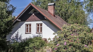 Ein Haus mit Satteldach, zwei Fenstern und einem Schornstein.
