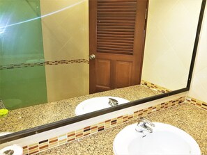 A bathroom with two sinks, a mirror, and a wooden door. - Thepthip Mansion Pratumak - Studio Sleeps 2 (Pattaya)