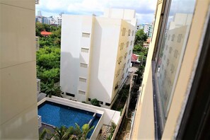 A residential building with a swimming pool, surrounded by greenery and other buildings. - Thepthip Mansion Pratumak - Studio Sleeps 2 (Pattaya)