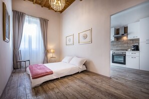 Een slaapkamer met een bed, een stoel, een bureau en een raam met gordijnen.