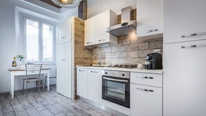 A modern kitchen with white cabinetry, a built-in oven, and a coffee machine.