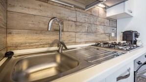 A modern kitchen with a stainless steel sink, a gas stove, and wooden wall paneling.