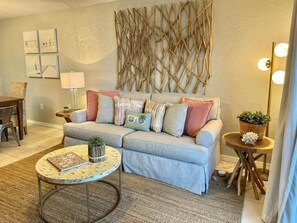 Ein Wohnzimmer mit Sofa, Couchtisch, Wandbild und Lampe.