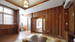 Ein traditioneller japanischer Raum mit Tatami-Bodenbelag, einem niedrigen Tisch und einer verschiebbaren Tür zu einem Schlafzimmer.