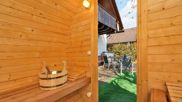 Uma sauna com paredes de madeira, um banco e um balde de madeira.