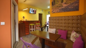 A cozy living area with a sofa, a wooden table, and a TV mounted on the wall. - Hostel Stella Di Notte (Belgrade)