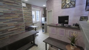 A modern kitchen with a built-in stove, a sink, and a refrigerator. There are two benches and a window providing natural light. - Hostel Stella Di Notte (Belgrade)