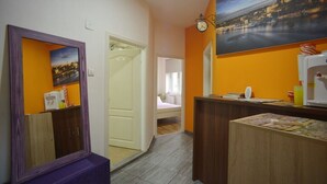 A hotel room with a wooden desk, a mirror, a painting of a cityscape, and a bed with a pink blanket. - Hostel Stella Di Notte (Belgrade)