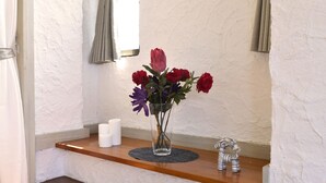 A clear glass vase with flowers on a wooden shelf. - Bay Side Okinawa (Onna)