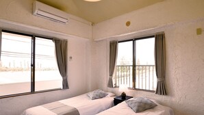 A room with two beds, a window, an air conditioning unit, and a lamp. - Bay Side Okinawa (Onna)
