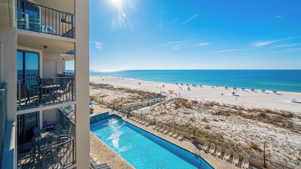 Un hôtel doté d'une piscine, offrant une vue sur la plage et comprenant plusieurs balcons.
