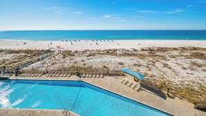 Un complexe hôtelier de bord de mer doté d’une piscine, de chaises longues et de parasols.