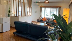 A modern hotel lobby with a blue sofa, a round coffee table, and a wooden partition. - Nomu House (Chatan)