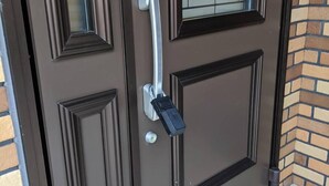 A brown door with a glass panel, a doorbell, and a mailbox. - Nomu House (Chatan)